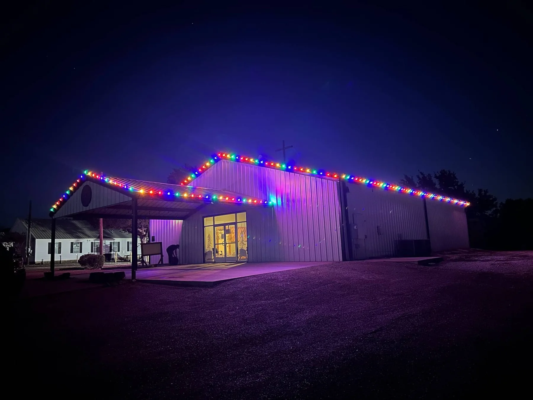Multi-color roofline lighting outlining a church exterior at night
