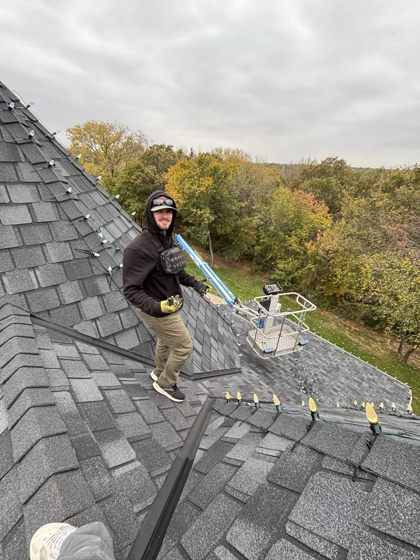 A Lutgen Lights crew member installing C9 bulbs along a roofline from a lift