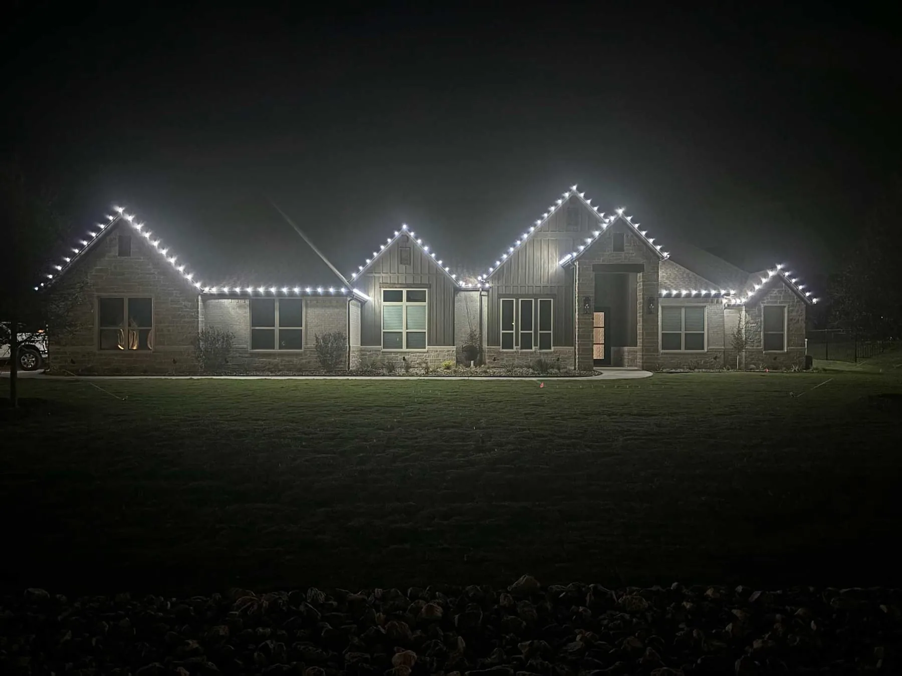 Crisp pure white roofline lighting on a stone home at night
