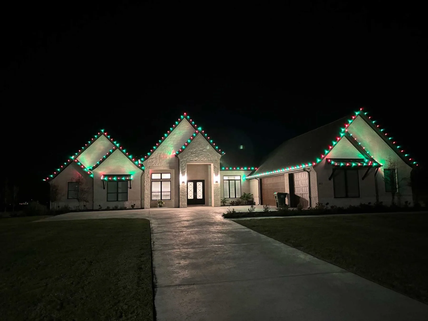 Red and green roofline lighting on a stone home